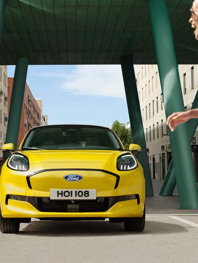 Kvinde går foran Ford Puma Gen-E i farven electric yellow