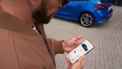 Mand står med mobil i FordPass-appen