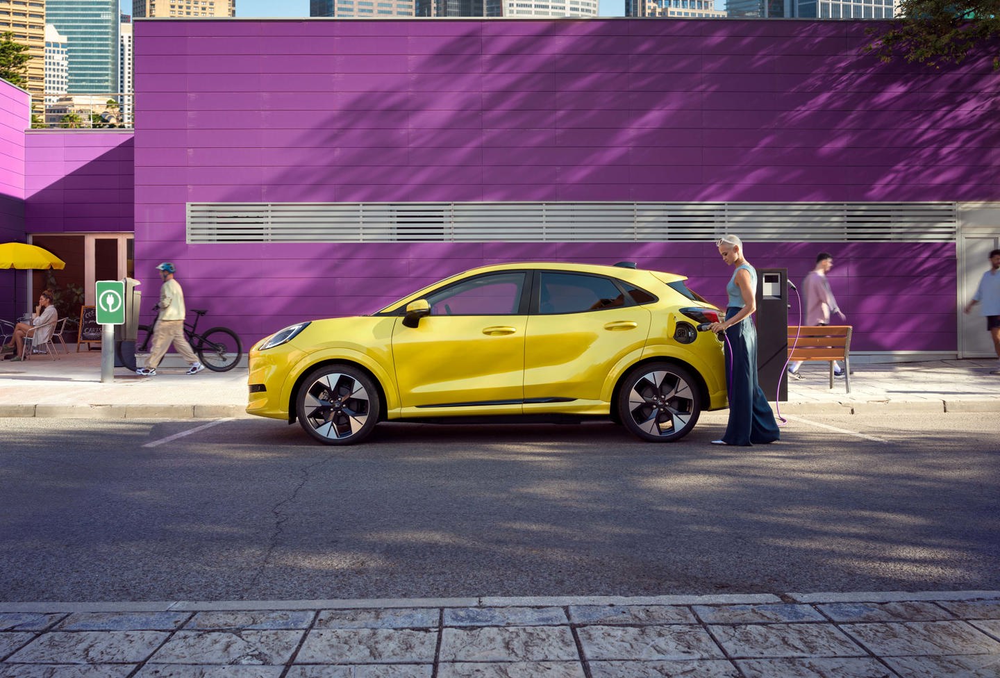 Kvinde oplader Ford Puma Gen-E set fra siden parkeret i byen
