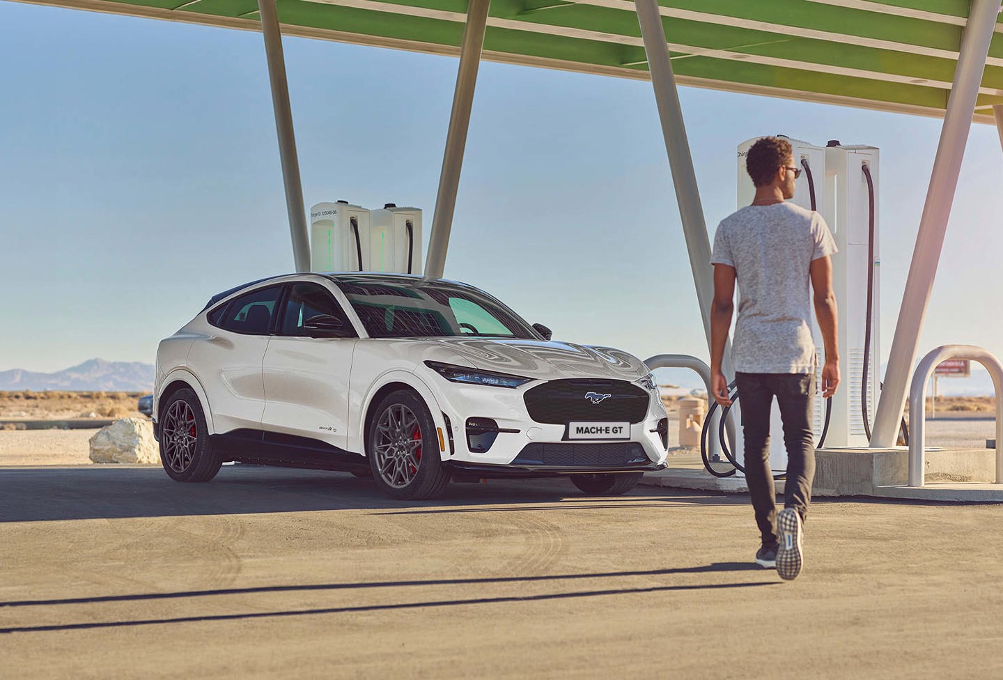 En hvid SUV parkeret udendørs med en person stående i nærheden, vist med kraftig digital forvrængning og glitch-effekter.