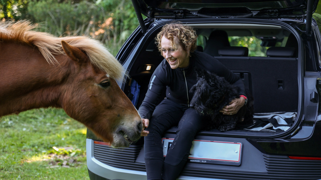 Rikke sidder i åbent bagagerum i Ford Explorer med hund og hest ved siden af