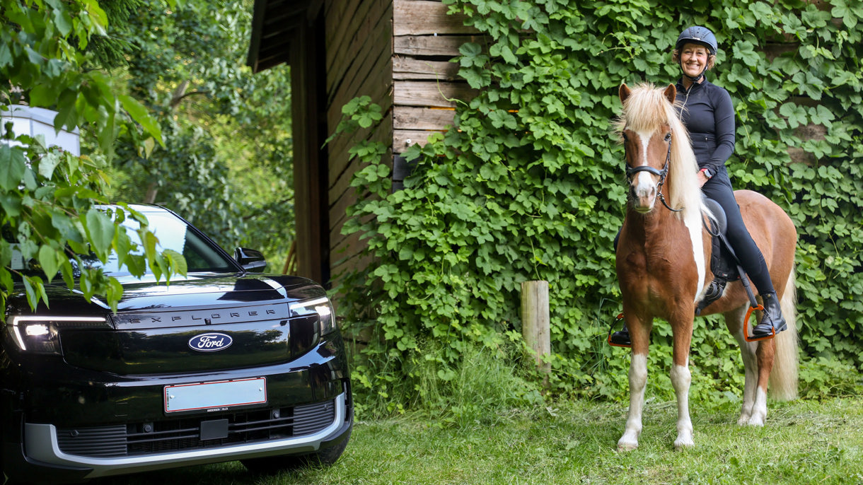 Rikke sidder på hest ved siden af parkeret Ford Explorer
