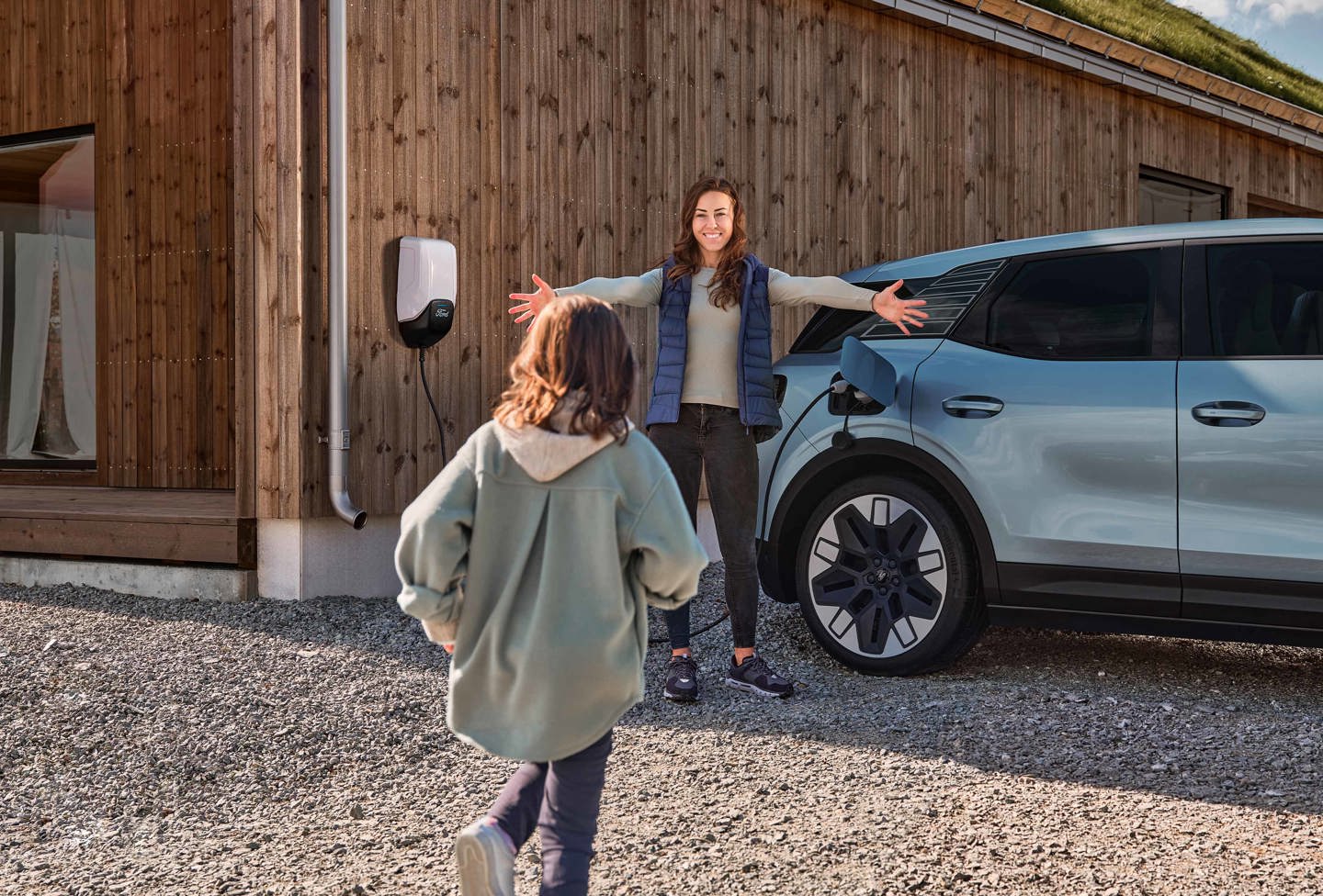 Barn løber hen til kvinde med åbne arme som står ved Ford Explorer