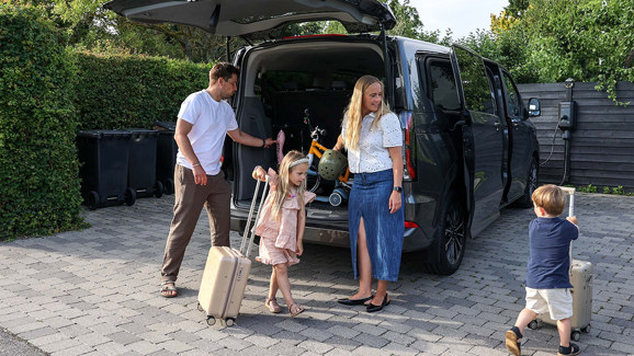 Familien Aarris står ved siden af deres bil